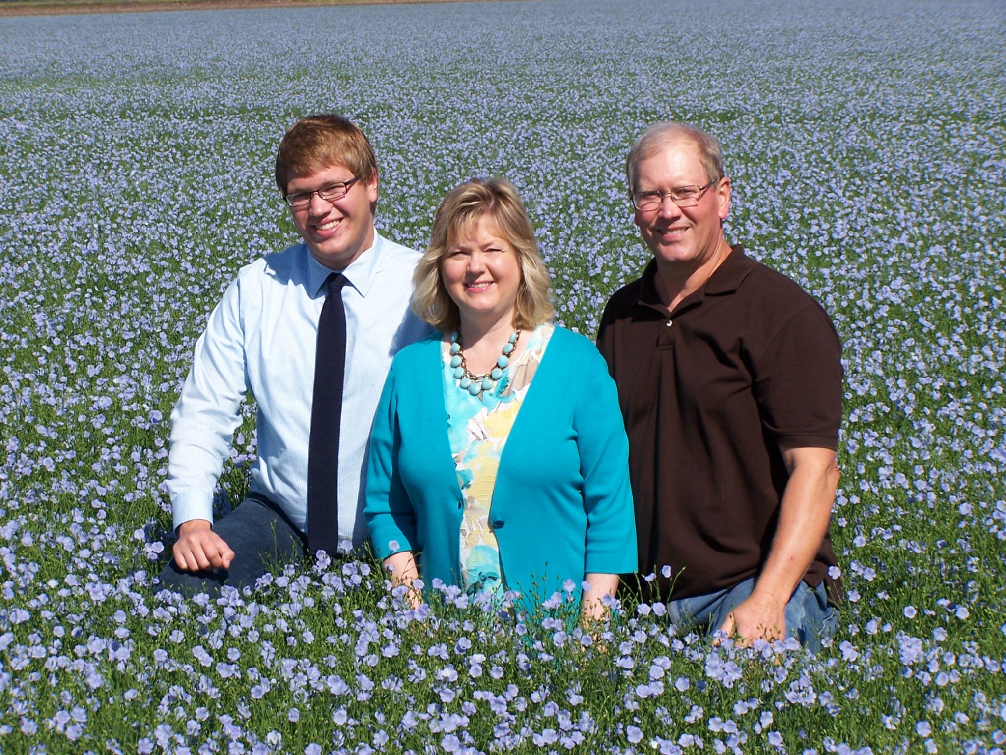 Justin, Esther and Mark Hylden in blooming flax field